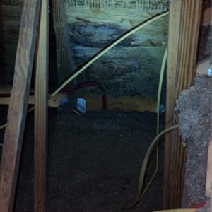 mold-found_0004_IMG_9585 Georgia Mold Mutts, LLC A dimly lit attic or crawl space with exposed wooden beams, electrical wiring, insulation, and visible areas suitable for mold detection along the wall and floor.